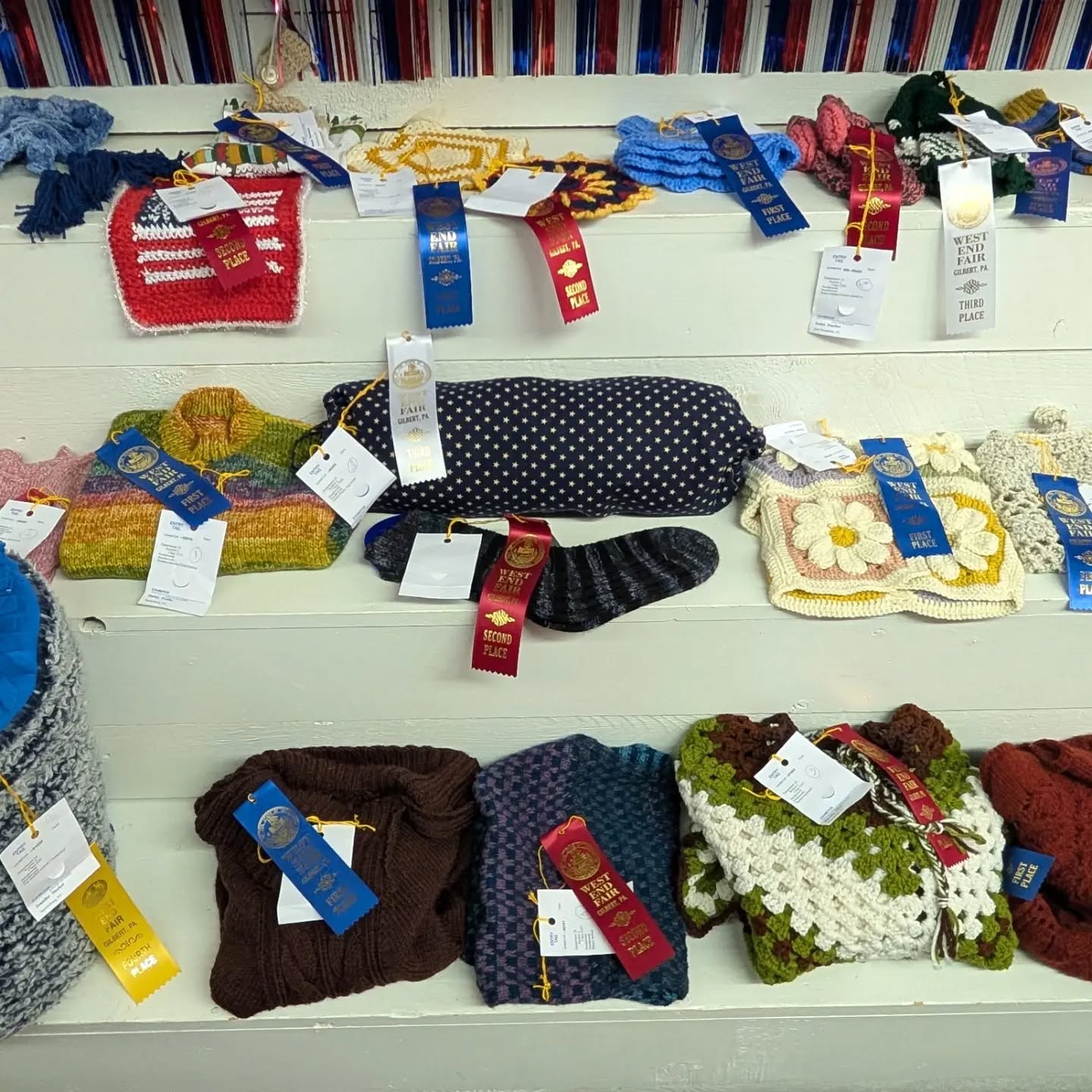 A table with fiber arts submissions displayed, each containing a ribbon.