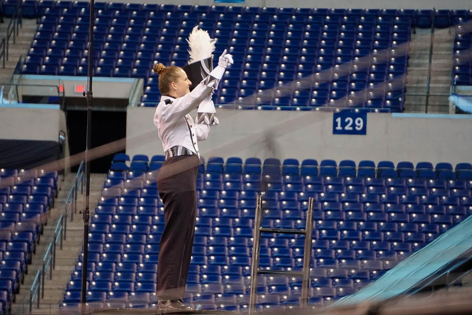 A drum major on their podium saluting the crowd.