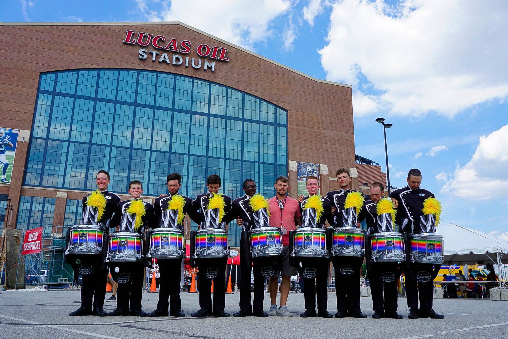 A drum corps snare line with their instructor, posing.