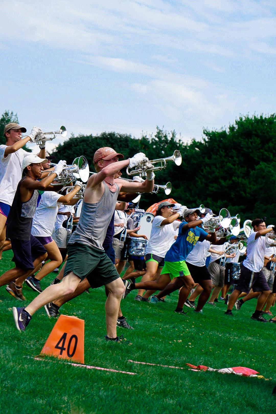 A group of trumpet players jazz running during rehearsal.