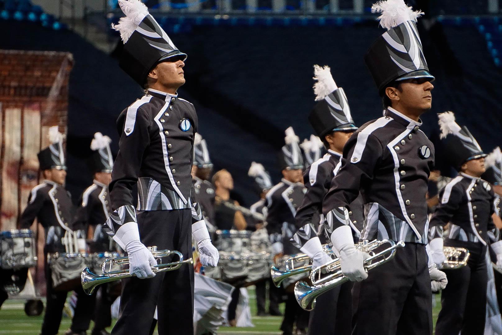 Members of a drum corps mid-show with stern facial expressions.