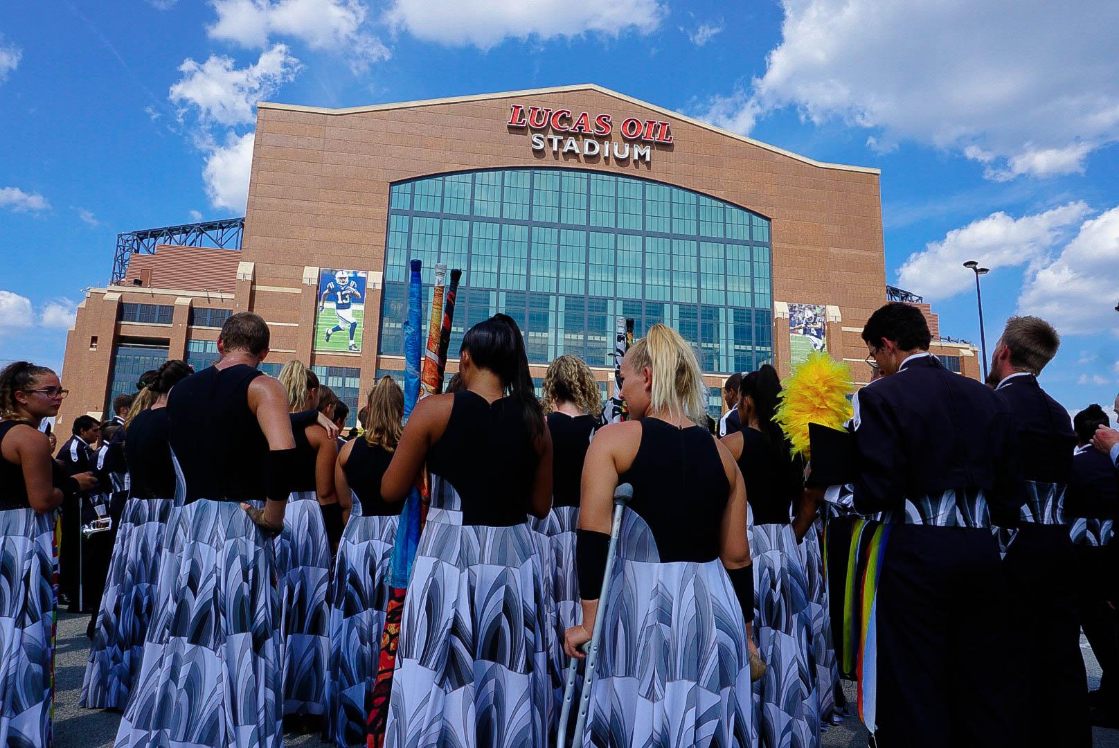 A drum corps huddled with their heads down, focusing before a show.